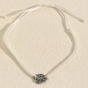 Detailed macro shot of a white braided Halloween bracelet with alloy spiderweb charm