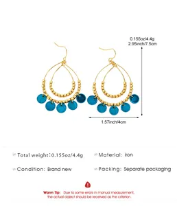 Detailed view of boho double teardrop shell earrings with gold plating and blue charms.