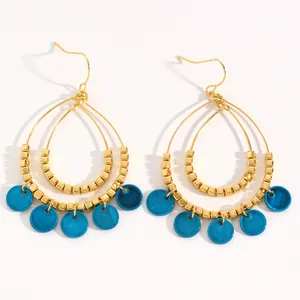 Detailed view of ethnic double-layer teardrop gold earrings with blue shell discs