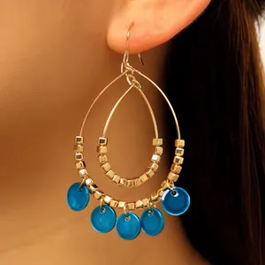 Close-up detail of vintage ethnic double-layer teardrop earrings with blue shell pendants