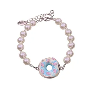 Elegantes Perlenarmband mit blauem Emaille-Donut-Anhänger und rosa Kristallen auf Weiß