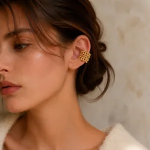 Detailed shot of a textured multi-layer gold beaded ear cuff on a model's ear.