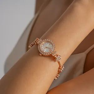 Close-up of rose gold watch bracelet with crystal flower accents and clasp closure