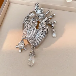 Exaggerated anatomical heart-shaped brooch with sparkling rhinestones and pearl drops