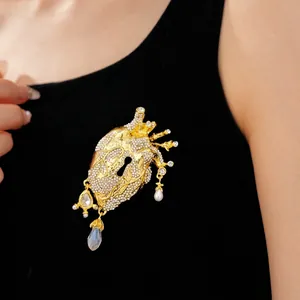 Ornate anatomical heart brooch with keyhole design, rhinestones, and pearl charms