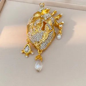 Detailed view of a gold anatomical heart brooch adorned with rhinestones and pearls