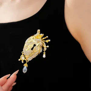 Exquisite detail of a gold anatomical heart brooch with rhinestones and pearl drops