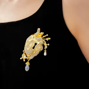 Close-up of anatomical heart brooch with keyhole and pearls on black fabric
