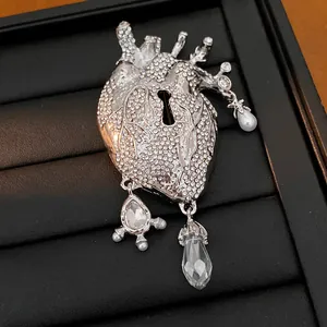 Detailed close-up of anatomical heart brooch featuring keyhole design and dangling crystals