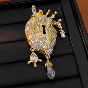 Detailed view of gold anatomical heart brooch with rhinestones, pearls and keyhole