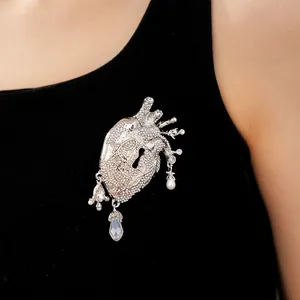 Detailed macro shot of a rhinestone anatomical heart brooch with keyhole and pearls.