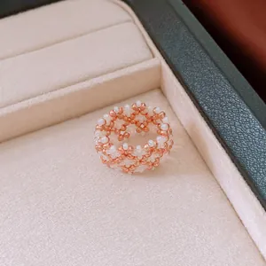 Detailansicht eines handgefertigten Rings mit roségoldenen und weißen Glasperlen