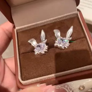 Primer plano de pendientes de conejo con circón en forma de corazón en caja de terciopelo