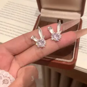 Primer plano detallado de pendientes de conejo con circón de corazón y acabado plateado fino