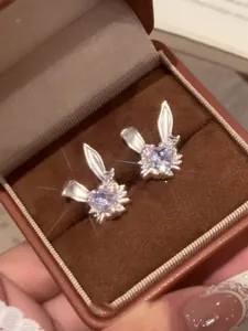 Primer plano detallado de pendientes de conejo con circonitas en una caja de joyas