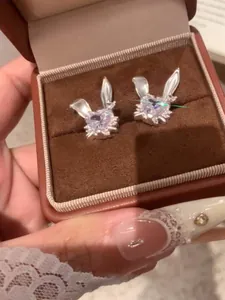 Detalle de pendientes de botón de conejo con circonita morada en forma de corazón