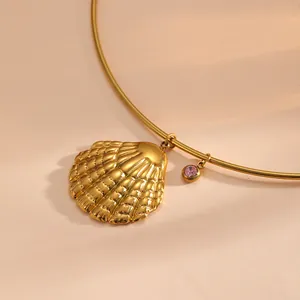 Détail d'un collier à pendentif coquillage doré avec une petite pierre rose