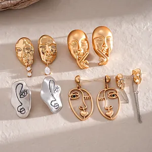 Collection of artistic abstract face mask earrings in matte gold and silver finishes