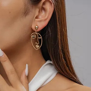 Macro detail of a matte gold abstract face mask earring worn by a model with style