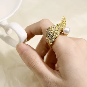 Macro view of gold-plated wing ring with sparkling crystals and a white pearl