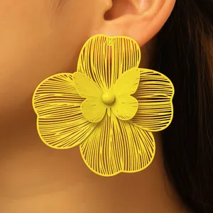 Detailed macro view of vibrant yellow oversized hollow flower earrings with butterfly