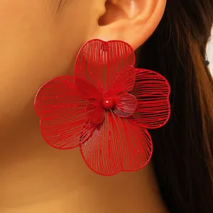 Macro detail of oversized red hollow-out flower earring with butterfly center