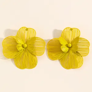 Detailed macro view of oversized yellow hollow-out flower earrings featuring butterfly center