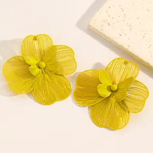 Detailed view of oversized yellow hollow flower earrings with butterfly center accent