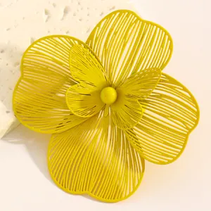Detail of oversized hollow yellow flower jewelry with delicate layered metal petals.