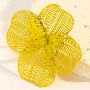 Close-up of bright yellow oversized hollow-out flower earring with central butterfly detail.