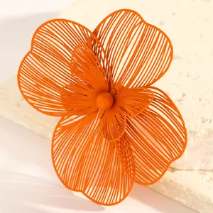 Close-up of large orange filigree flower jewelry showing double-layer petal detail