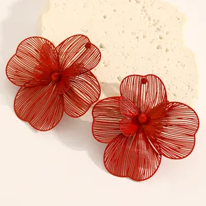 Detailed macro view of oversized red hollow flower jewelry set on a stone prop.