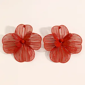 Detail view of oversized red cutout flower earrings with double-layered filigree design