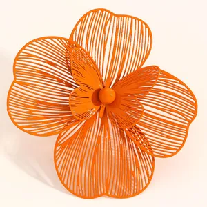 Macro detail of oversized orange hollow flower jewelry with delicate butterfly center.