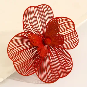 Close-up of oversized red hollow metal flower earring showing intricate texture