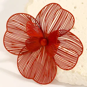 Detailed macro view of an oversized red hollow flower jewelry piece with layered petals
