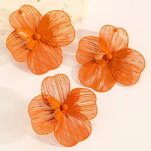 Detailed view of vibrant orange oversized hollow floral earrings and open ring set.