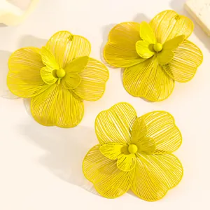 Detailed view of oversized yellow hollow flower earrings and matching ring with butterfly center