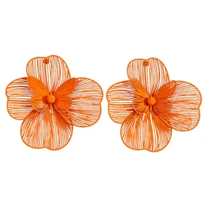 Macro view of oversized orange hollow-out flower earrings with butterfly centers.