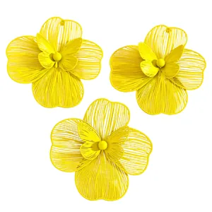Detailed view of oversized yellow hollow flower earrings and ring with butterfly center.
