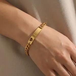 Goldfarbenes Panzerarmband mit herzförmig ausgeschnittenem Plättchen am Handgelenk