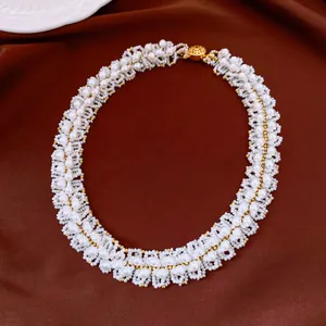 Dettaglio di una collana di perle intrecciate in stile vintage con accenti dorati su seta