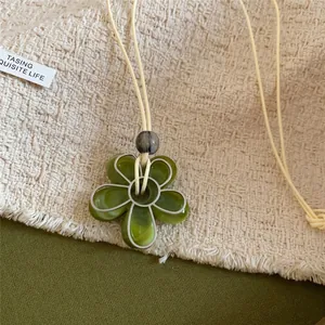 Collier élégant avec pendentif fleur en résine verte et cordon crème pour femmes
