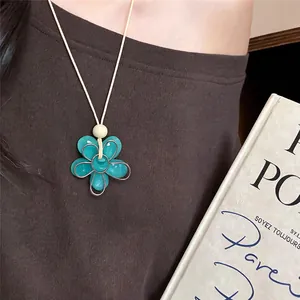 Gros plan d'un pendentif fleur en résine turquoise avec des détails en fil d'argent sur cordon.