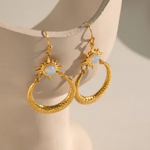 Detailaufnahme goldener Sonne-Mond-Ohrringe mit Opal und Hammerschlag.