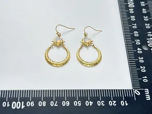 Detailansicht von Edelstahl-Ohrringen mit Sonne, Mond und Opal neben einem Lineal