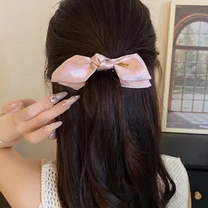 Elegant pink satin bow hair clip featuring a minimalist design for a sweet hairstyle