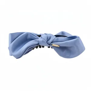 Elegant light blue fabric bow hair clip with a minimalist gold tag accent for women