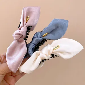 Close-up of elegant satin bow hair clips in pink, blue, and white with acrylic teeth.