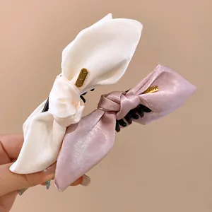 Close-up detail of elegant satin fabric bow hair clips in cream and dusty pink colors